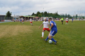 Zwei Fußballspieler im Wettkampf um den Ball auf einem Rasenplatz während eines Spiels.
