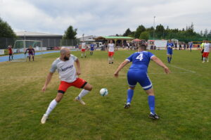 Zwei Fußballspieler auf dem Spielfeld, einer in weißem Trikot und der andere in blauem Trikot.