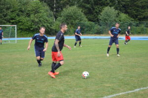 Eine Gruppe von Fußballspielern in blauen und schwarzen Trikots spielt auf einem Rasenplatz.