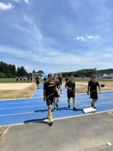 Eine Gruppe von Fußballspielern in schwarzen Trikots mit gelben Akzenten, die auf einem Sportplatz gehen.