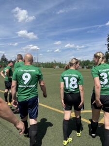 Spieler einer Fußballmannschaft in grünen Trikots mit Nummern auf dem Rücken auf dem Spielfeld.