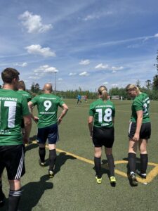 Spieler einer Fußballmannschaft in grünen Trikots mit Nummern auf dem Rücken auf dem Spielfeld.