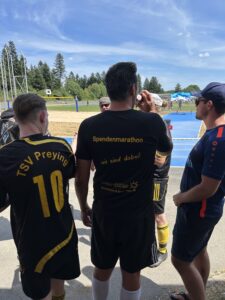 Zwei Fußballspieler in Trikots stehen nebeneinander und trinken Wasser während eines Events.