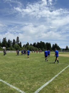 Gruppe von Fußballspielern in blauen Trikots beim Training auf einem Sportplatz.