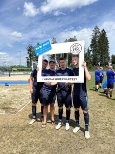 Vier Fußballspieler posieren mit einem großen Rahmen, der den Text '#MEHRALSDUERWARTEST' enthält.