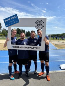 Vier Fußballspieler posieren mit einem großen Rahmen, der das Logo von Made in FRG zeigt.