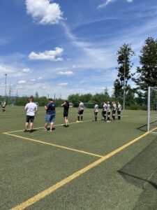 Gruppe von Personen, die auf einem Fußballplatz während des Trainings stehen und sich aufwärmen.