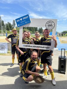 Sechs Fußballspieler posieren mit einem Schild, das den Hashtag '#MEHRALSDUERWARTEST' zeigt.