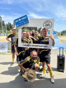 Eine Gruppe von Fußballspielern posiert mit einem großen Rahmen und einem Schild bei einem Sportevent.