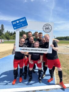 Eine Gruppe von Fußballspielern posiert mit einem großen Rahmen und einem Schild in der Hand.