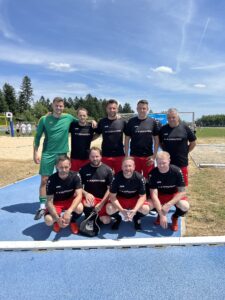Eine Fußballmannschaft in schwarzen und roten Trikots posiert auf dem Spielfeld nach einem Spiel.