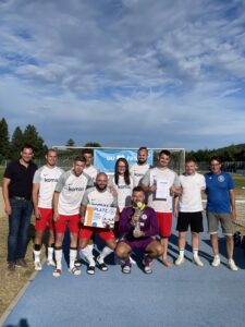Eine Fußballmannschaft posiert mit einem Pokal und einer Urkunde nach einem Spiel.