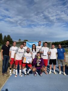 Eine Fußballmannschaft posiert mit einem Pokal und Urkunden nach einem Turnier.