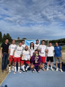 Eine Fußballmannschaft posiert mit einem Pokal und einer Urkunde nach einem Turnier.
