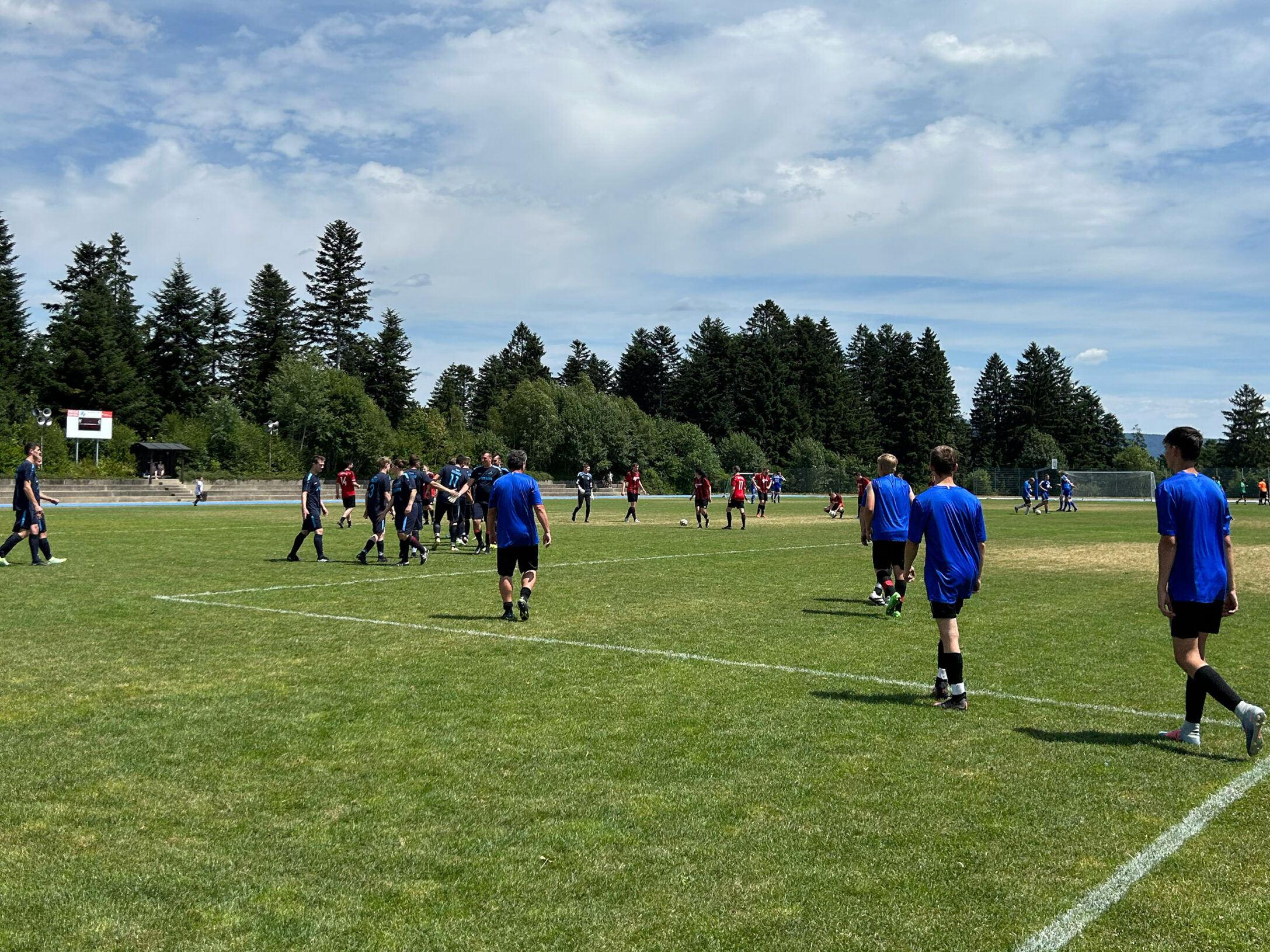 Gruppen von Spielern in blauen und roten Trikots auf einem Fußballfeld während eines Spiels.