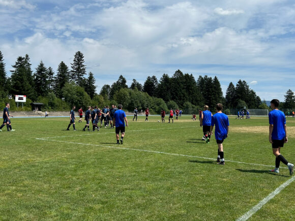 Gruppen von Spielern in blauen und roten Trikots auf einem Fußballfeld während eines Spiels.