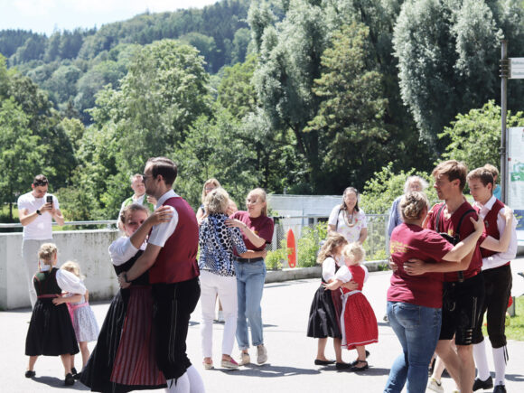 Gruppe von Menschen in traditioneller Kleidung, die auf einer Veranstaltung tanzen und feiern.