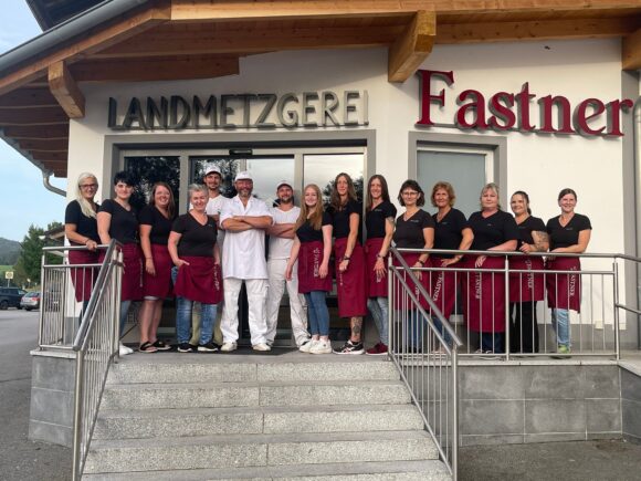 Gruppe von Mitarbeitern der Landmetzgerei Fastner, die vor dem Geschäft stehen.