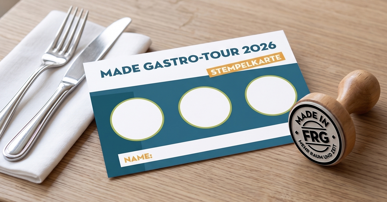 Die MADE Gastro-Tour 2026 Stempelkarte liegt neben Besteck und einer Stempelmarke mit dem Logo MADE in FRG auf einem Holztisch.