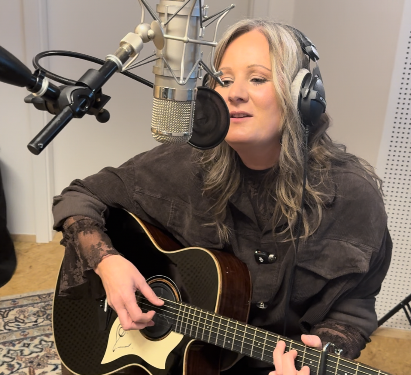 Mit Kopfhörern singt Marion Bauer am Studiomikrofon und begleitet sich auf der Gitarre zu ihrem Heimatlied für Freyung-Grafenau.