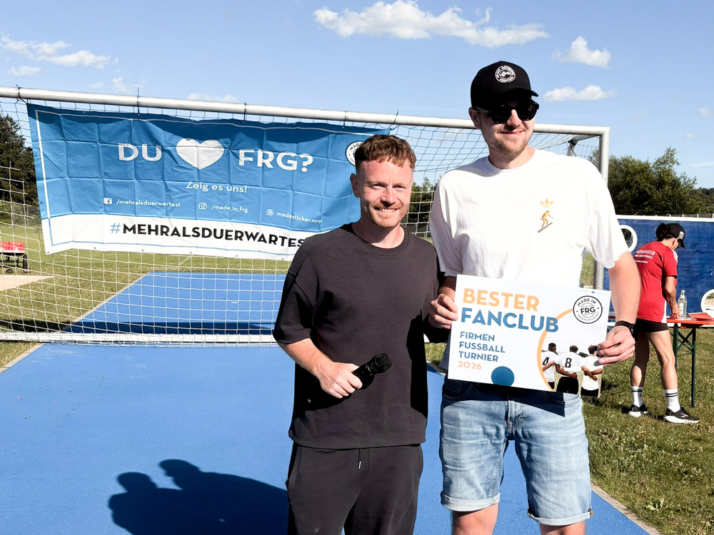Bei der Ehrung zum besten Fanclub des Firmen-Fußballturniers 2026 hält ein Mann die Auszeichnung vor dem Fußballtor.