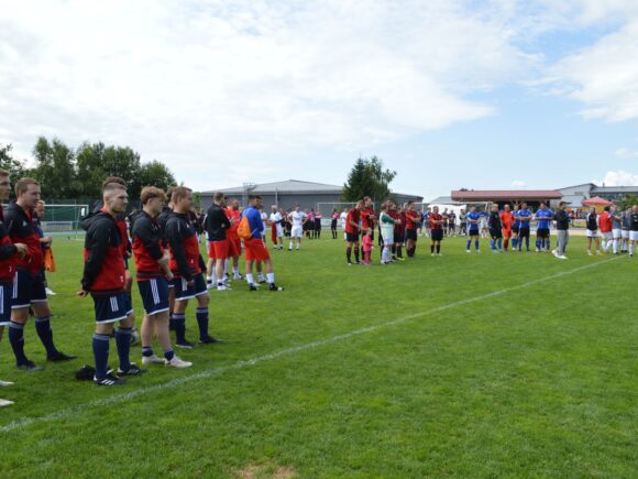 Auf dem Sportgelände des TV Freyung stehen Firmenteams in verschiedenen Trikots beim Firmenfußballturnier 2025 auf dem Rasen.