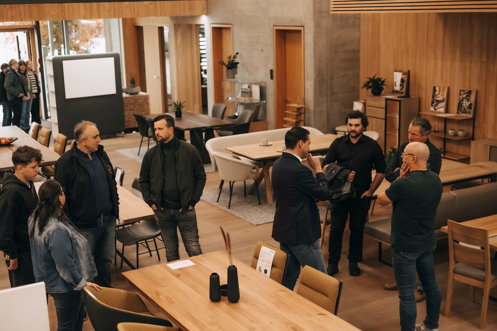 Besucher sprechen bei der Langen Nacht der Wirtschaft in einem Ausstellungsraum zwischen Holztischen und Möbeln miteinander.